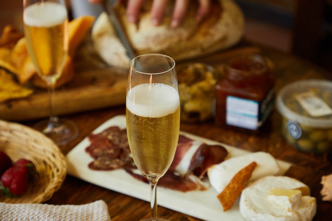 Close-up of charcuterie board with cheese, bread, and sparkling wine for a perfect gourmet evening.
