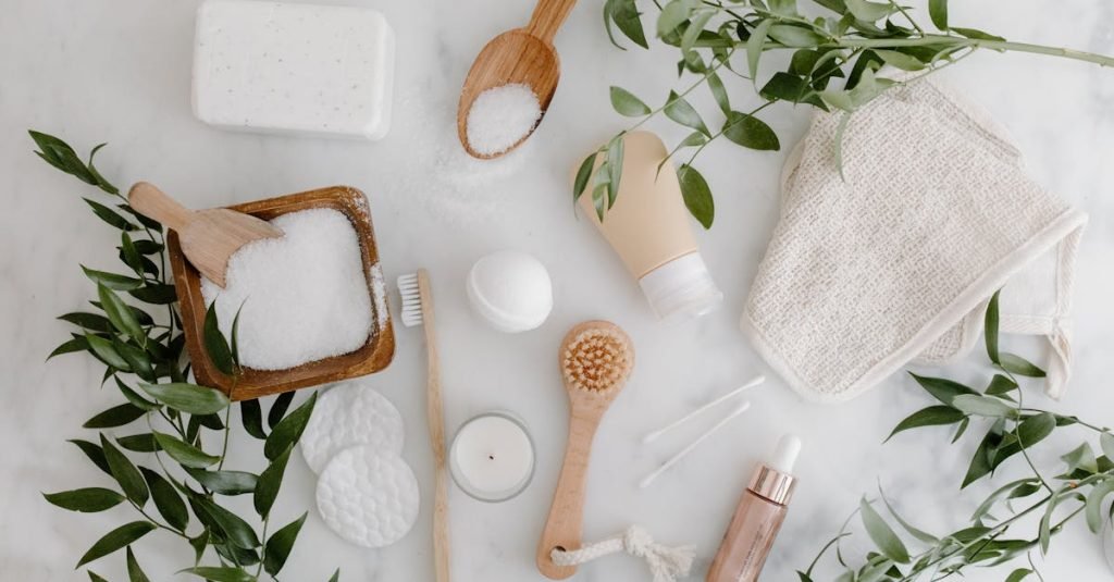 Elegant flat lay of organic bath essentials including soap, brush, and salts with greenery.